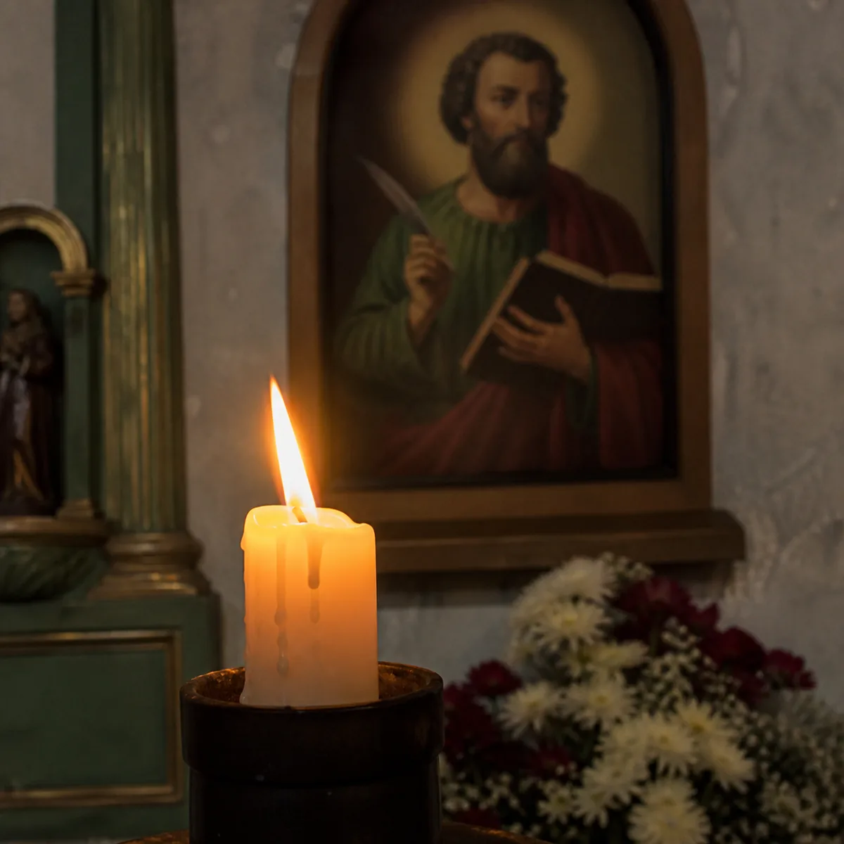 Interior sencillo de una iglesia mexicana con una vela encendida frente a una imagen antigua de un evangelista sosteniendo un libro y una pluma